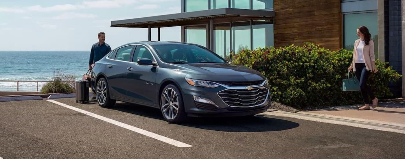 Used Car Dealership - 2020 Chevy Malibu - Grey.jpg A grey 2020 Chevy Malibu is shown parked outside of a hotel.