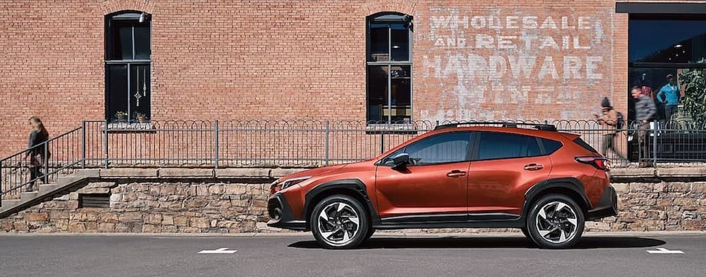 car dealer near Chapel Hill - 2024 Subaru Crosstrek - Orange.jpg An orange 2024 Subaru Crosstrek parked near a hardware store.