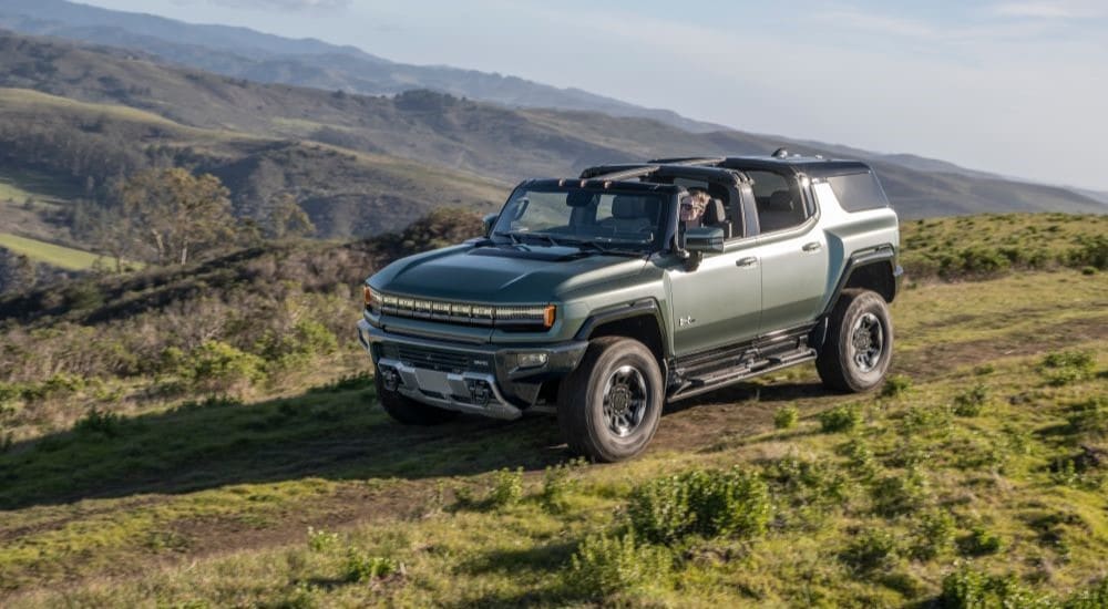 Car Dealership - 2024 GMC Hummer EV - Trail.jpg A green 2024 GMC Hummer EV is shown driving on a mountain trail.
