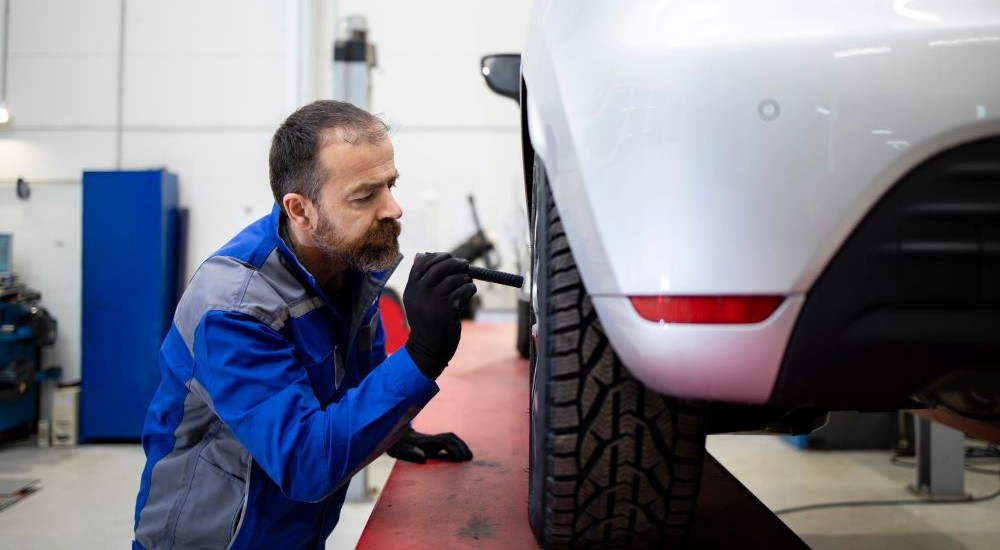 A mechanic is shown inspecting a vehicle.