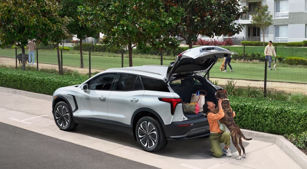 A person is shown playing with a dog near a white 2025 Chevy Blazer EV.
