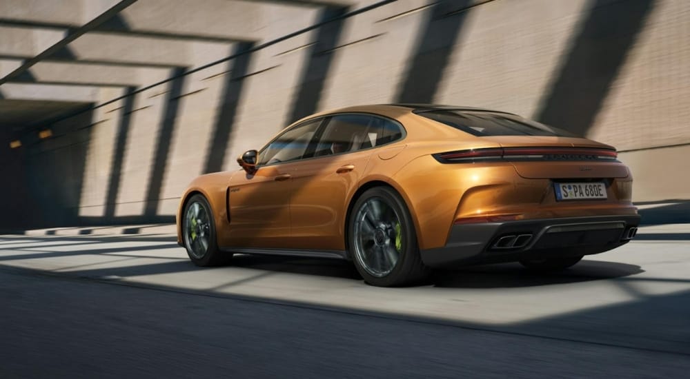 An orange 2025 Porsche Panamera Turbo S E-Hybrid is shown from the side.