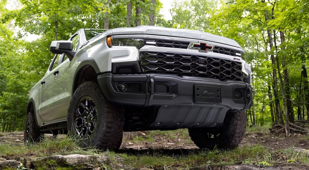 White 2024 Chevy Silverado 1500 LT parked in a forest from a dealer with trucks for sale in Raleigh.