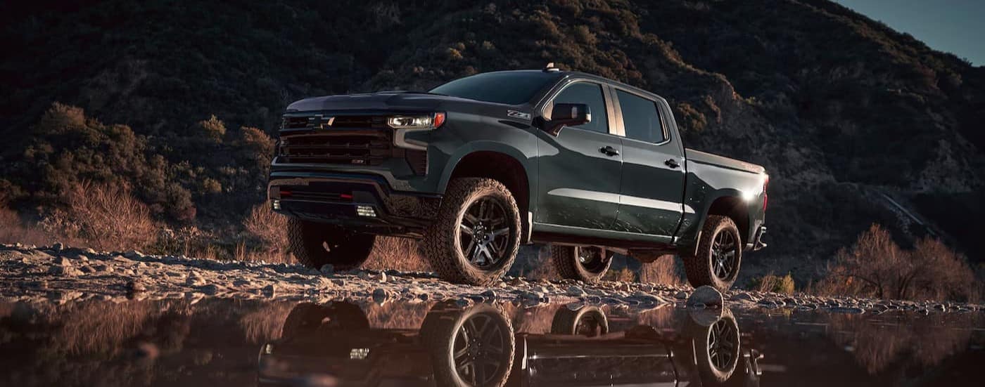 truck%20for%20sale%20near%20Cary%20-%202025%20Chevy%20Silverado%201500%20Z71%20-%20Reflection.jpg A green 2025 Chevy Silverado 1500 Z71 parked near water.